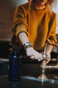 femme ouvrant le robinet avec de l'eau jaunâtre